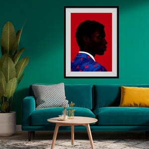 May include: A framed art print featuring a profile portrait of a person against a red background. The person is wearing a blue jacket with red heart-shaped patterns. The artwork is displayed on a teal wall above a teal sofa.