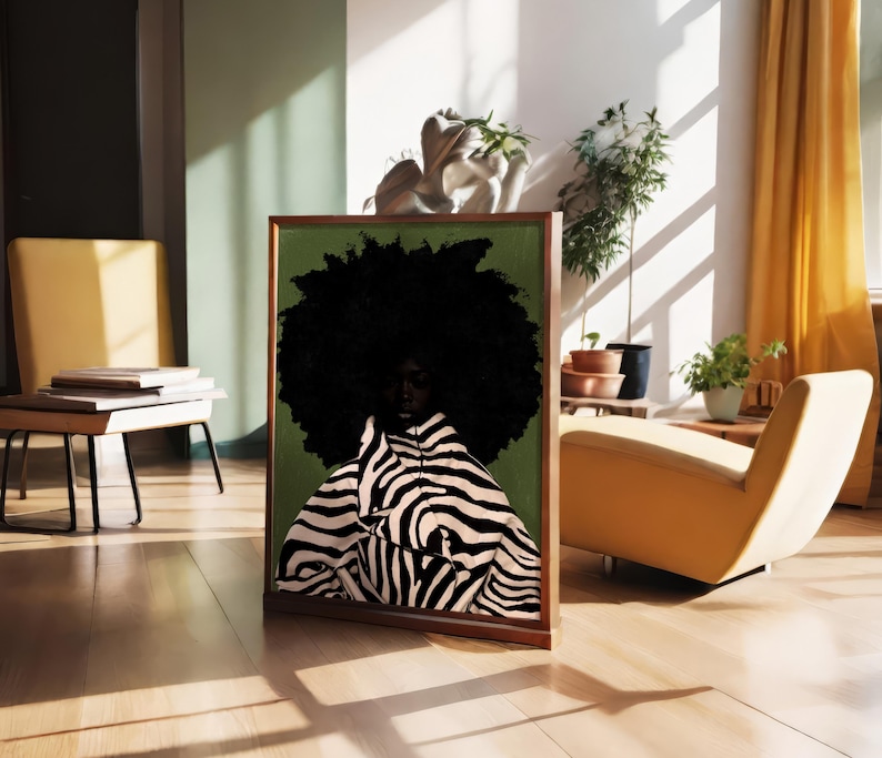 Op de afbeelding: Een ingelijste kunstdruk met een persoon met een grote, donkere afro en kleding met zebraprint tegen een groene achtergrond. Het kunstwerk wordt tentoongesteld in een lichte kamer met een houten vloer, een gele stoel en planten.