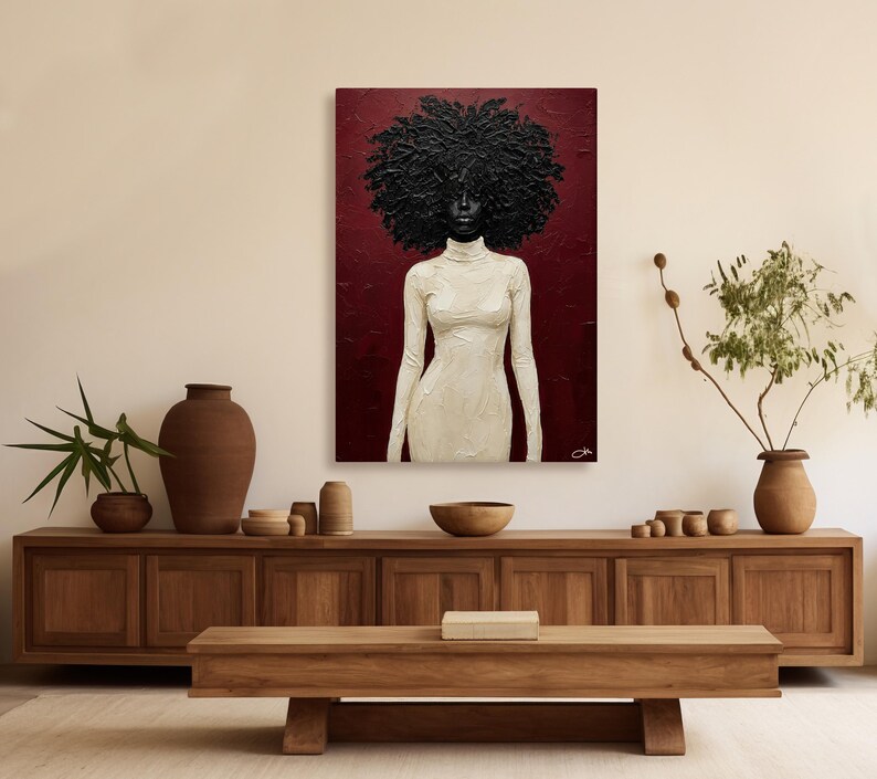 May include: An abstract painting of a person with a large, textured black afro and a white turtleneck dress against a deep red background. The artwork is displayed above a wooden cabinet with decorative items.