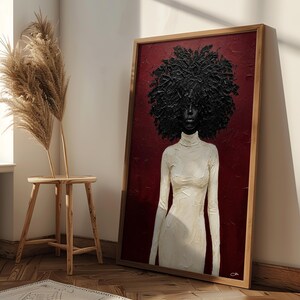 May include: A framed artwork featuring a woman with a large, textured black afro and a white turtleneck dress against a deep red background. The artwork is in a wooden frame and leans against a wall.