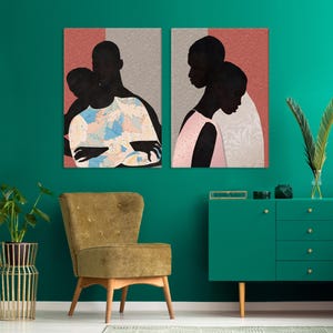 May include: Two rectangular wall art prints featuring stylised silhouettes of people against a textured coral and grey background. The left print shows figures in a blue and white patterned shirt, while the right print depicts figures in a pink garment.
