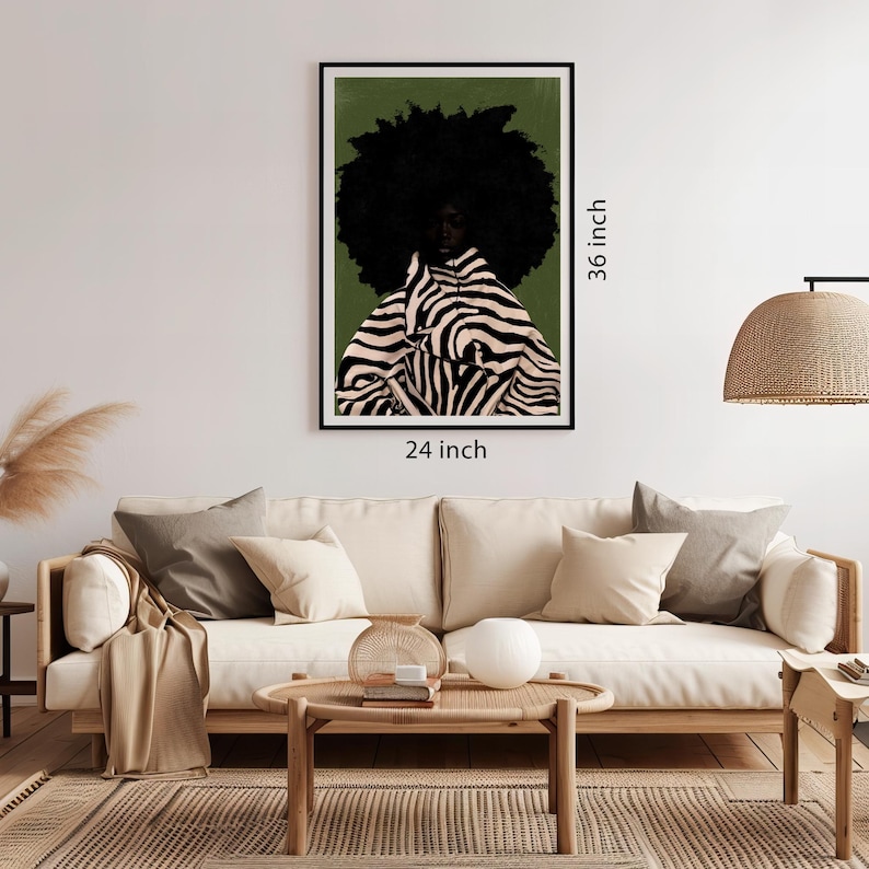 Op de afbeelding: Een ingelijste kunstdruk met een persoon met een grote zwarte afro en een jas met zebraprint. Het kunstwerk is 61 cm breed en 91 cm hoog. De achtergrond is een gedempt groen en de lijst is zwart. De kunst wordt boven een beige bank weergegeven.