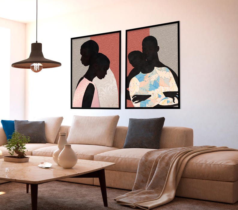May include: Two framed wall art prints featuring silhouettes of people. The left print shows two figures in profile against a pink and grey background. The right print depicts two figures embracing, one wearing a blue and white patterned shirt.