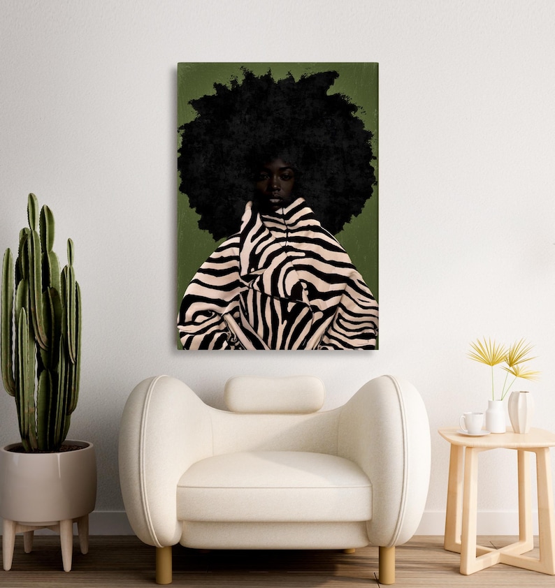 Op de afbeelding: Een canvas print met een portret van een persoon met een grote afro en een zebra-gestreept kledingstuk. De achtergrond is olijfgroen. Het kunstwerk wordt boven een witte fauteuil getoond.