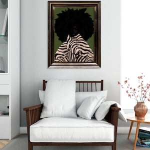 Op de afbeelding: Een ingelijst kunstwerk toont een persoon met een grote zwarte afro en een zebra-gestreept kledingstuk tegen een groene achtergrond. Het kunstwerk hangt boven een houten fauteuil met witte kussens. Een kleine bijzettafel met een vaas bloemen staat naast de stoel.