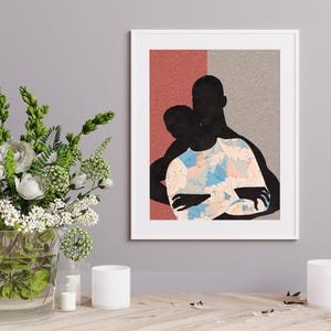 May include: A framed art print featuring a silhouette of two figures embracing. The figures are black, with one wearing a shirt decorated with a light blue, peach, and white floral pattern. The background is split into a textured red and grey section.