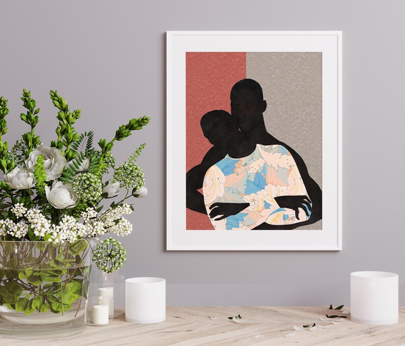 May include: A framed art print featuring a silhouette of two figures embracing. The figures are black, with one wearing a shirt decorated with a light blue, peach, and white floral pattern. The background is split into a textured red and grey section.