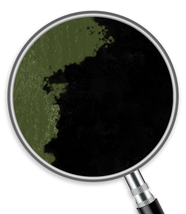 Op de afbeelding: Een close-up door een vergrootglas toont een getextureerd oppervlak verdeeld in twee gebieden. De ene kant is een gedempt olijfgroen, de andere is diepzwart. Het vergrootglas heeft een zilveren rand en een zwarte handgreep.