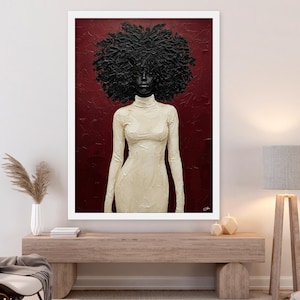 May include: A framed art print featuring a woman with a large, textured afro and a cream-colored, long-sleeved dress. The background is a deep red, and the artwork is displayed in a white frame, creating a striking contrast.