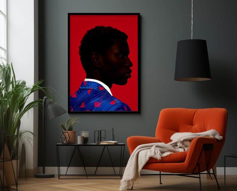 May include: A framed art print featuring a profile of a person with dark skin against a red background. The person wears a blue jacket with red heart-shaped designs and a white collar. The artwork hangs above an orange armchair.