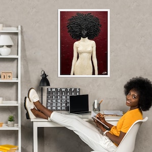 May include: A framed art print featuring a portrait of a person with a large, textured afro and wearing a cream-colored turtleneck dress. The background is a deep red. The art is displayed on a gray wall.