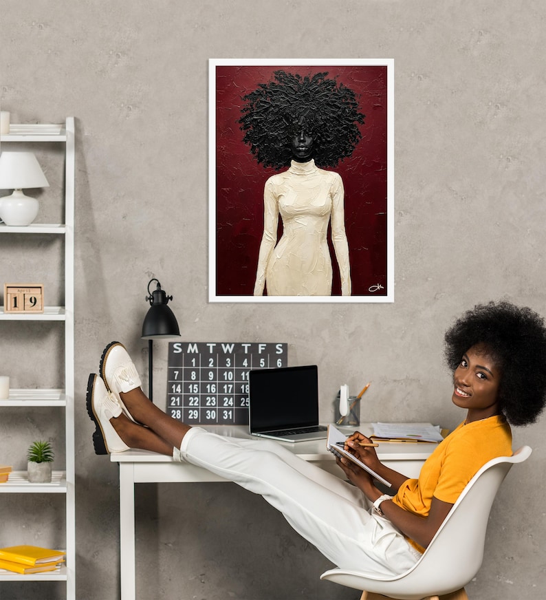 May include: A framed art print featuring a portrait of a person with a large, textured afro and wearing a cream-colored turtleneck dress. The background is a deep red. The art is displayed on a gray wall.