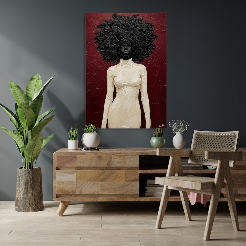May include: An oil painting depicts a Black figure with a large, textured afro and a cream-colored turtleneck dress against a deep red background. The artwork is displayed above a wooden cabinet with a plant and decorative items.