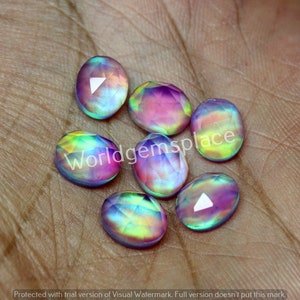 Puede incluir: Siete piedras preciosas ovaladas iridiscentes con un arcoíris de colores, incluyendo rosa, morado, azul, verde y amarillo.