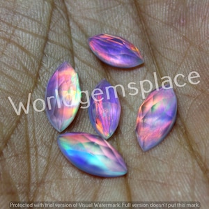 Puede incluir: Cinco piedras preciosas iridiscentes, de forma ovalada y facetadas, con un arcoíris de colores, incluyendo rosa, morado, azul y verde.