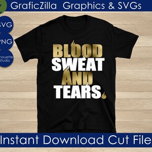 Op de afbeelding: Een zwart T-shirt met een gouden afbeelding waarop "BLOOD SWEAT AND TEARS" staat met vlammen boven en onder de tekst.