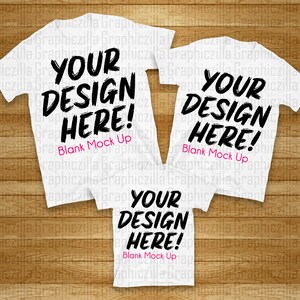 Puede incluir: Tres camisetas blancas con el texto "YOUR DESIGN HERE! Blank Mock Up" impreso en ellas. Las camisetas est&aacute;n dispuestas en forma de pir&aacute;mide sobre una superficie de madera.