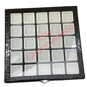 May include: Black leather ring box with a clear lid and 36 individual compartments for storing rings. The box has a silver latch.
