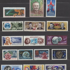 Può includere: Una collezione di francobolli vintage dell'URSS, con immagini di cosmonauti, esplorazione spaziale e ritratti. I francobolli presentano vari disegni, colori e denominazioni, con testo in cirillico. I francobolli sono disposti su uno sfondo nero.