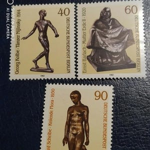 Puede incluir: Tres sellos postales alemanes con esculturas de bronce. Los sellos muestran figuras de Georg Kolbe, Ernst Barlach y Richard Scheibe. Cada sello tiene una denominación y el texto "DEUTSCHE BUNDESPOST BERLIN".