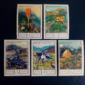 Peut inclure: Ensemble de timbres-poste vintage de l'URSS, représentant des illustrations colorées de fleurs et de paysages de montagne. Chaque timbre a un design unique, avec du texte en cyrillique et la dénomination dans les coins inférieurs.