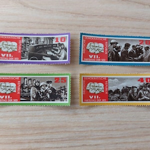 Op de afbeelding: Vier vintage postzegels met afbeeldingen van mensen en gebouwen. Elke postzegel heeft een andere kleur rand: paars, blauw, groen en geel. De postzegels bevatten Duitse tekst, waaronder "DEMOKRATISCHE REPUBLIK" en "VII. PARTEITAG DER SED."