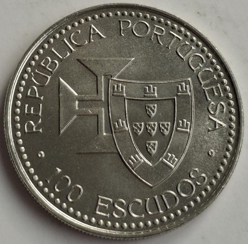 Puede incluir: Una moneda de plata de 100 escudos de Portugal. La moneda presenta las palabras "REP&Uacute;BLICA PORTUGUESA" y "100 ESCUDOS" alrededor del borde. El centro de la moneda tiene un escudo y un dise&ntilde;o en forma de cruz.