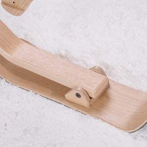 以下が含まれることがあります： 湾曲した木製ハンドルと平らな木製ベースを持つ木製ソリ。ソリは明るい木材で作られており、自然な仕上げになっています。