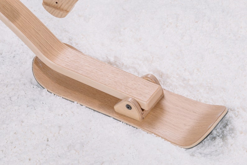 以下が含まれることがあります： 湾曲した木製ハンドルと平らな木製ベースを持つ木製ソリ。ソリは明るい木材で作られており、自然な仕上げになっています。