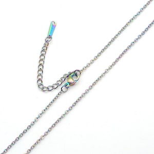 May include: A delicate, iridescent chain necklace with a lobster clasp and adjustable chain. The necklace has a rainbow finish, with hues of blue, purple, and green. The clasp is marked "S. STEEL".