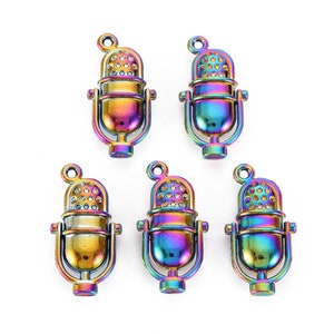 May include: Five iridescent microphone charms with a rainbow finish. Each charm features a detailed microphone design with a circular top, a central body, and a U-shaped stand. The charms have a small loop at the top for attaching to jewelry or other crafts.