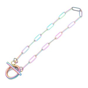 May include: Iridescent chain necklace with an oval link design and a toggle clasp. The necklace has a rainbow finish, with hues of blue, green, and pink. The toggle clasp is a circular ring with a straight bar.