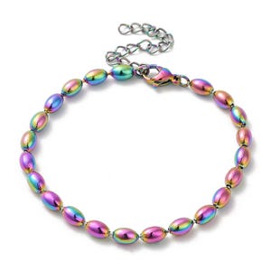 May include: A rainbow-colored beaded bracelet with an adjustable chain and lobster clasp. The oval beads display a gradient of colors, including purple, green, and gold. The bracelet is made of metal and is designed to be worn on the wrist.