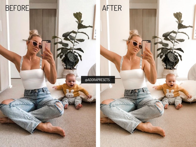 May include: A woman and a baby are sitting on the floor. The woman is wearing a white tank top with black straps that say "Make a Wish" and blue jeans. The baby is wearing a yellow sweater with a white bunny on it. The woman is holding a phone and taking a selfie. The background is a light brown wall with a plant in a pot.