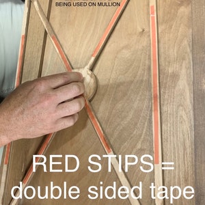 May include: A close-up of a wooden frame with red double-sided tape strips along the edges. The text "EXAMPLE OF TAPE BEING USED ON MULLION" and "RED STIPS = double sided tape" is visible. The text "C & C Specialties" is in the bottom right corner.
