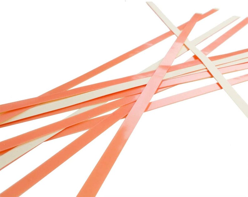 May include: A pile of thin, flexible strips of tape. The tape is peach on one side and white on the other side.