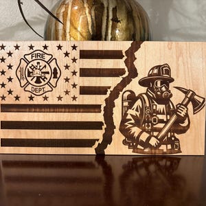May include: A wooden plaque with a distressed American flag design and a firefighter with an axe. The firefighter is wearing a helmet and a gas mask. The plaque has the words "Fire Dept." on it.