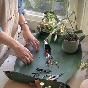 person caring for houseplants on an indoor garden mat to contain mess.