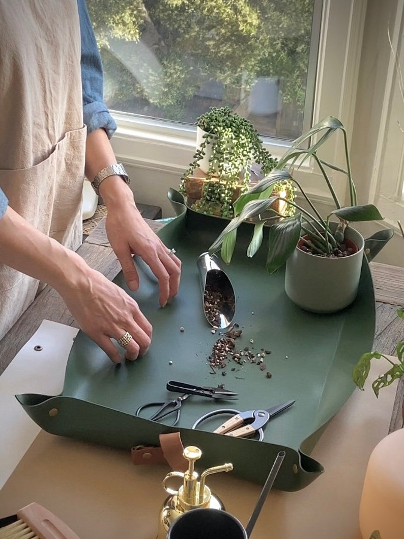 person caring for houseplants on an indoor garden mat to contain mess.