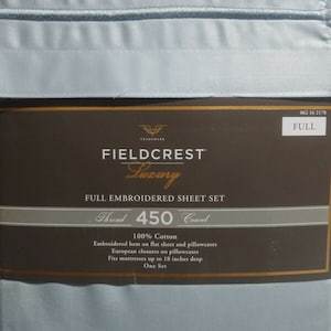 May include: A full-size, light blue Fieldcrest Luxury embroidered sheet set. The packaging displays the brand name, thread count, and features, including 100% cotton and embroidered hems. The set fits mattresses up to 18 inches deep.