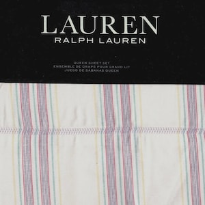 May include: A white queen-sized sheet set with a striped pattern in shades of pink, green, purple, and yellow. The packaging features the Lauren Ralph Lauren logo and the text "Queen Sheet Set, Ensemble de Draps pour Grand Lit, Juego de Sabanas Queen."
