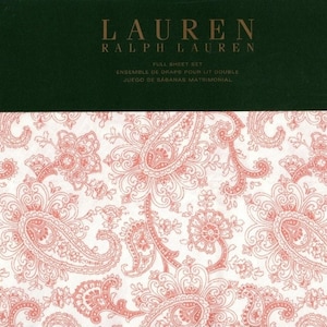 May include: A white sheet set with a paisley pattern in a light pink color. The sheet set is labeled "Lauren Ralph Lauren" and includes the text "Full Sheet Set, Ensemble de Draps pour Lit Double, Juego de Sabanas Matrimonial".