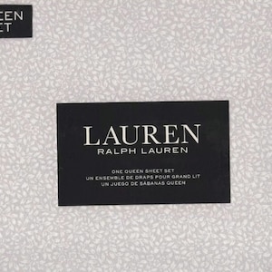 May include: A white queen-sized sheet set with a floral pattern. The packaging features the Lauren Ralph Lauren logo and the text "One Queen Sheet Set, Un Ensemble de Draps Pour Grand Lit, Un Juego de Sabanas Queen."