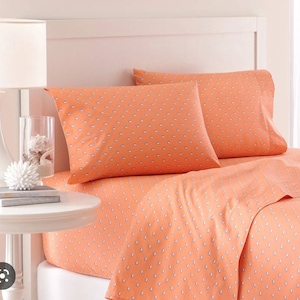 May include: A coral orange bed sheet set with a white and gray patterned design. The set includes a fitted sheet, flat sheet, and two pillowcases.