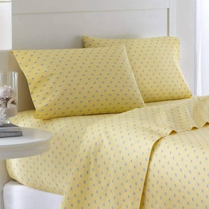 May include: A yellow bed sheet and pillowcases with a small blue fish pattern. The bedding is made of soft, breathable fabric.