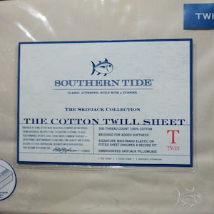 May include: A white twin-sized cotton twill sheet set from Southern Tide's Skipjack Collection. The packaging features a blue and white label with the brand name, product details, and a fish logo. The sheet set includes a flat sheet, fitted sheet, and a standard pillowcase.