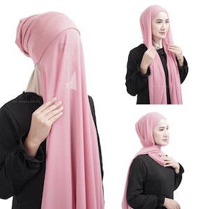 May include: A pink hijab, a traditional head covering, is shown in multiple views. The fabric drapes softly, with a light, airy appearance. The hijab is worn in different styles, showcasing its versatility and design.