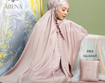 May include: A light pink prayer garment set, including a head covering and flowing robe, with a matching small pillow and mat. The set is made of a silky material and features the brand name "AILUNA". The words "FREE SAJADAH" are also visible.
