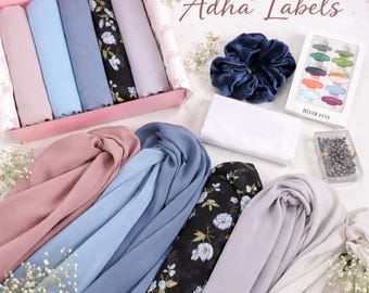 May include: A collection of colorful hijabs, including solid colors and floral patterns, are displayed with accessories like a velvet scrunchie and hijab pins. The image is labeled "Adha Labels."
