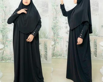 May include: A black maxi dress with long sleeves and a matching headscarf. The dress has a simple design and is made of a soft, flowing fabric.